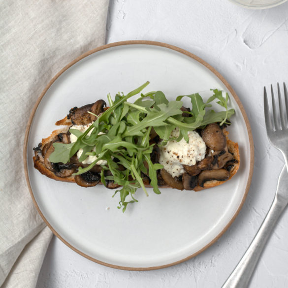 mushroom arugula toast ready to eat with a glass of wine