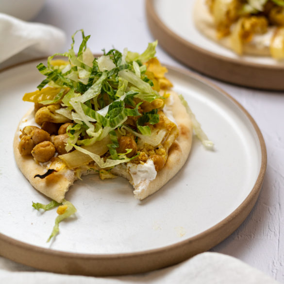 Sheet pan vegetable shawarma severed over naan and topped with greens