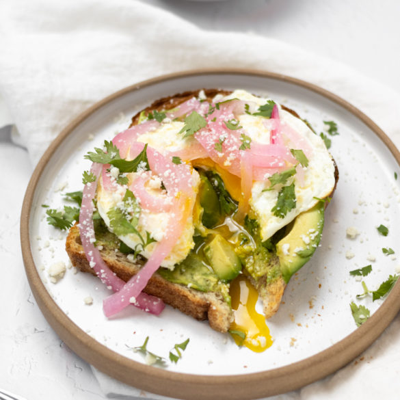 Calif Avocado Toast sliced so that the over easy egg yolk is running down the toast